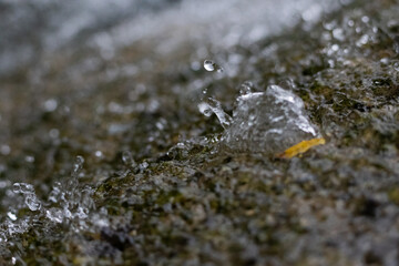 Close-up of clear water flowing over a textured rock surface in nature. Natural macro background symbolizing freshness, motion, and purity. Perfect for design, spa, or environmental concepts.