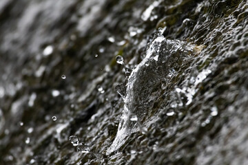 Macro photo of water splashing on a wet rock surface in nature. Dynamic texture background showing motion and freshness, perfect for design, environmental, or natural concept projects