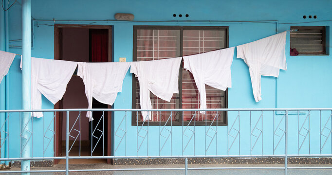 Clothes hanging for to dry on the clothesline, old aged house facade in India, lifestyle and culture, decaying wall - Powered by Adobe