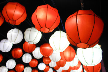 Red and white lantern lights with a balloon theme at night at an event.