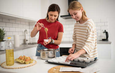 Happy Little Girl And Mother Baking Muffins In The Kitchen
