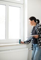 Girl Using Laser Measure On Window In White Empty Room