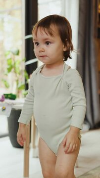 Toddler dancing and in a bright room, repeating movements while watching a cartoon. Happy, smiling little girl in a playful atmosphere. Vertical video. 