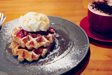 Waffles in a black plate with icing and ice cream