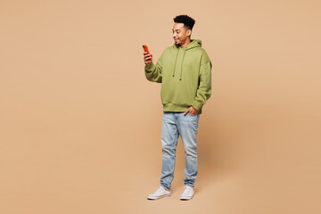 Full body young smiling happy man of African American ethnicity wears green hoodie casual clothes...