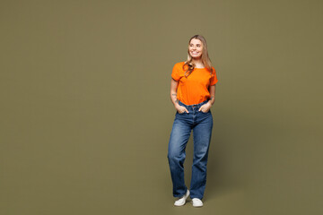 Full body young smiling happy cheerful Caucasian woman she wears orange t-shirt casual clothes look...