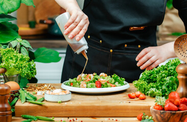 Chef skillfully prepares healthy salad, drops sauce on full plate, using fresh vegetables and vibrant ingredients