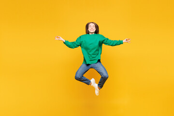 Obraz premium Full body young happy woman she wear green sweatshirt casual clothes jump high hold spreading hands in yoga om aum gesture relax meditate try to calm down isolated on plain yellow orange background.