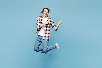 Obraz premium Full body young man he wears purple checkered shirt casual clothes jump high point index finger on area mockup isolated on plain pastel light blue cyan background studio portrait. Lifestyle concept.