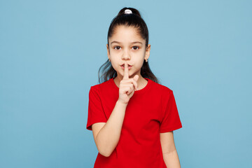 Little child kid girl 8-9 years old wears red t-shirt say hush be quiet with finger on lips shhh...