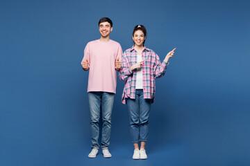 Fototapeta premium Full body young couple two friends family man woman they wear pink casual clothes together point index finger aside on area show thumb up isolated on plain blue background studio. Lifestyle concept.