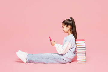 Full body young school girl 8-9 years old she wear blue casual clothes sit near stack of books hold...