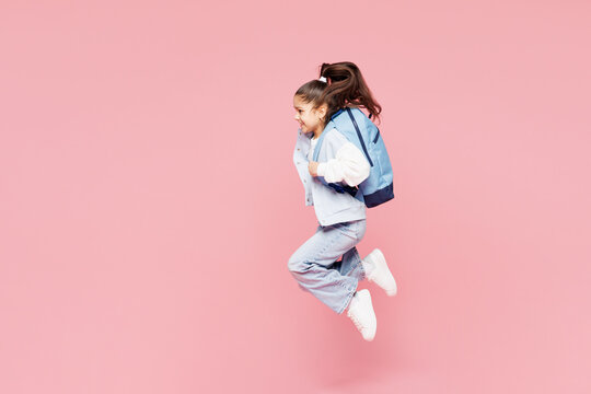 Full body young overjoyed excited fun cool school girl 8-9 years old wear blue casual clothes backpack hold books isolated on plain pink background children portrait. Childhood kids education concept.