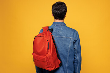 Back rear view young brunette boy student wearing blue jeans casual clothes orange backpack bag...
