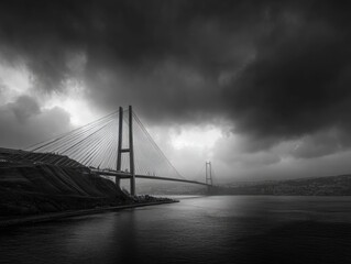 Fototapeta premium Dramatic monochrome shot of a cable-stayed bridge spanning a body of water under a brooding, dark sky