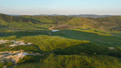 Fototapeta premium Buzău Green Hills Sunset. A serene landscape view captures rolling green hills in Buzău County, Romania, bathed in the warm hues of a sunset. 