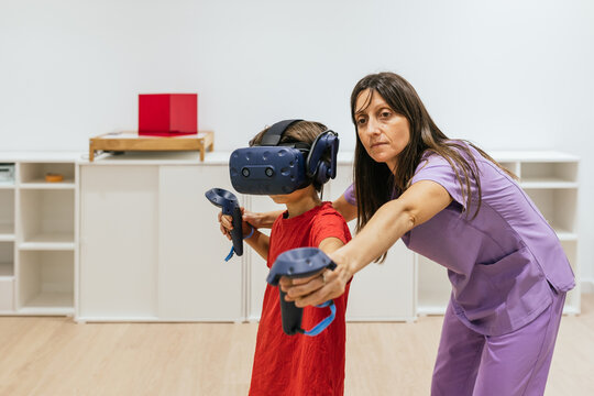 Child wearing virtual reality glasses playing with doctor assisting