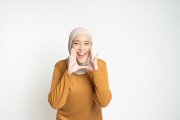 A joyful woman wearing a hijab and an orange top expresses enthusiasm with hand gestures, showcasing natural positivity and charm.