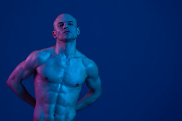 Confident man posing in a striking blue setting, showcasing a strong physique. This powerful image conveys a sense of strength and determination, using vibrant contrasts.