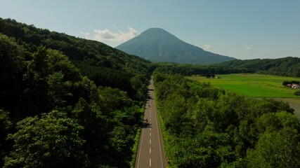 Aerial follows Japanese highway asphalted route to Mount Yotei's Crater and Surrounding Alpine Flora in Hokkaido