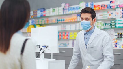 Female client choosing pills in pharmacy. Male pharmacist picking up medicine for woman. Man...