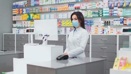 Female pharmacist looking at computer screen. Woman pharmacist working with inventory. Woman in...