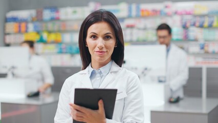 Female pharmacist standing near racks with cosmetics. Woman druggist conducting audit of new supply...