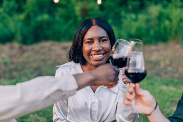Friends toasting red wine glasses smiling outdoors party celebration