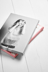 Black and white photo canvas print of joyful young girl, placed over another canvas with pink edge. The bottom canvas reveals its back side with staples securing the fabric to the wooden stretcher bar