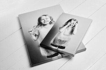 Two black and white canvas prints featuring a joyful girl, stretched on wooden stretcher bars with gallery wrapping. Displayed on a white wooden surface
