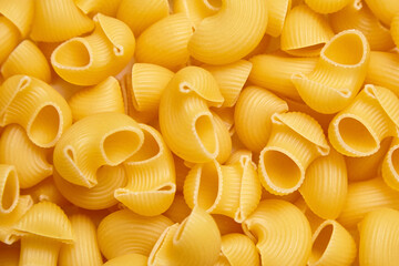 Detailed close-up of uncooked pipe rigate pasta showcasing its curved, ribbed structure and golden color, ideal for food textures or culinary backgrounds