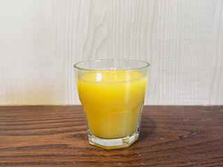 Glass of orange juice on wooden table.