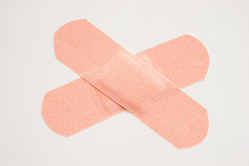 Two adhesive bandages crossed on white background