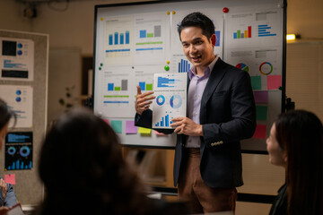A man is standing in front of a board with graphs and numbers