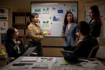 A group of people are standing around a white board with graphs on it