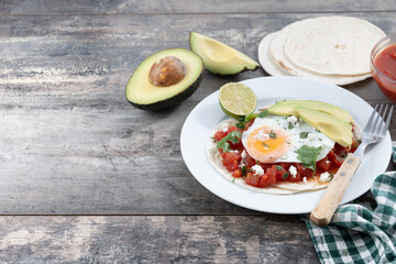 Huevos Rancheros on wooden table. Copy space. Traditional Mexican breakfast