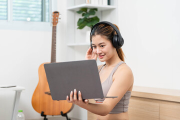 Yoga and Online Fitness. Young woman engaging in virtual yoga session with headphones and laptop.