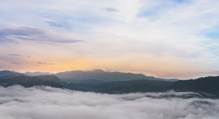 Sunrise sky,cloud over top of misty mountains range with visible silhouettes forest trees through the fluffy fog.Image Panoramic Landscape Natural background for screen wallpaper