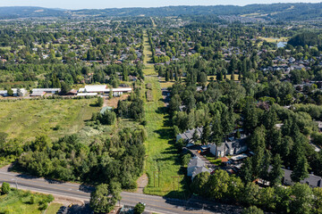 Aerial drone photo of aligned electrical utility poles running through a long green corridor in Cedar Mill, Portland, Oregon, surrounded by homes and trees in a suburban landscape