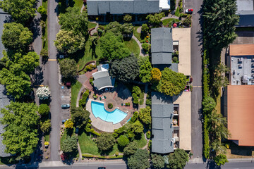 Aerial drone picture of a beautiful residential apartment complex in Cedar Mill, Portland, OR, captured at morning. Photo shows green courtyards, swimming pool, parking lots and housing buildings	
