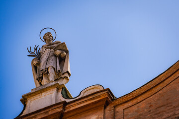 Marble statue of saint above church entrance, shot against clear blue sky in Italy 