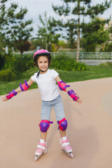 A little curly-haired girl rollerskates within the necessary facilities in the city. In a helmet...