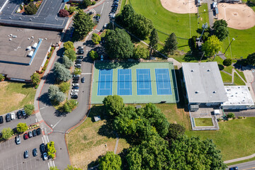 High resolution aerial drone picture of outdoor tennis courts and green fields near a high school in Cedar Mill, Portland, Oregon, captured on a clear summer day	
