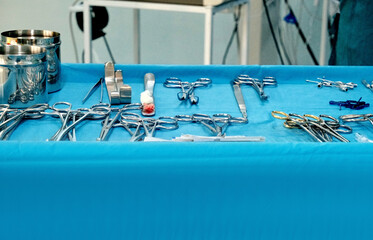Surgical instruments are laid out on a blue sterile drape; preparations for the operation are...