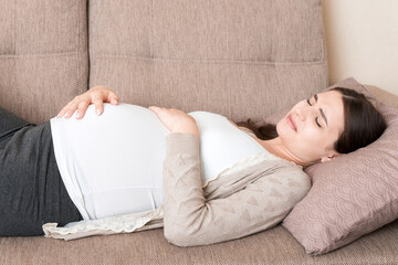 Pregnant woman with painful belly on sofa at home