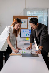 Two people are looking at a table with a laptop and papers