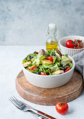 Vegetarian salad with lettuce, tomatoes, croutons and olives in a bowl on a wooden board