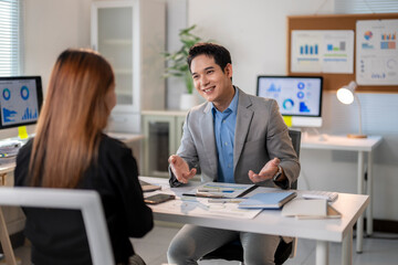 A man and a woman are sitting at a desk in a business setting