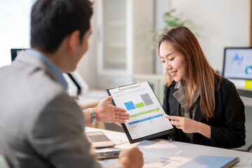 A man and a woman are looking at a presentation with graphs on a table