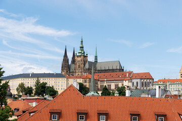 Fototapeta premium A picturesque view of Prague Castle and surrounding historical architecture, with reflections on the Vltava River under a cloudy sky